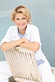 A blonde woman sitting backwards on a wooden chair