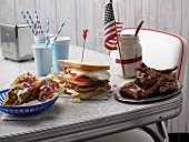 Taco shells, a club sandwich and spare ribs on a table (USA)