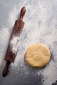 Wheat tortilla dough and a rolling pin on a floured work surface