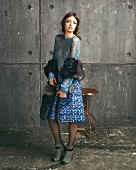 A brunette woman wearing a blue vintage blouse, a colourful tweed skirt and faux fur stola