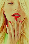 A blonde woman with red lipstick and fingernails
