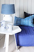 Blue and white table lamp on side table next to floor cushion