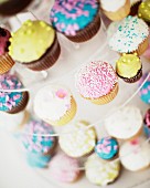 Colourfully decorated cupcakes for a wedding on a multi-tiered cake stand