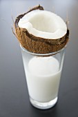A glass of coconut milk with half a coocnut