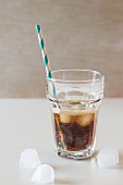 Glas Cola mit Eiswürfeln und Retro-Strohhalm