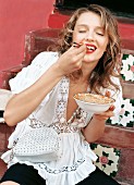 A young woman wearing a white folkloric blouse eating elation dish