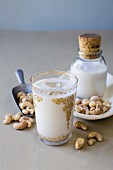 Cashew milk in gold-embossed glass with scattered cashew nuts