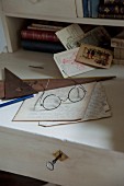 Spectacles and hand-written papers on white-painted writing desk