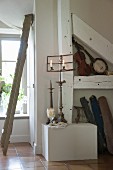 Lit candles in candle holders on antique music stand on platform with various old musical instruments in niche to one side