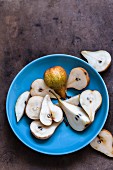 Fresh pears, whole and halved, in a blue bowl