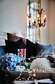 Blue hydrangea flower, glasses of Champagne and bead necklace on tray in bedroom
