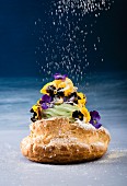 A sweet pastry with pistachio cream, pansies and icing sugar