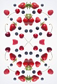 A digital composite of mirrored images of various berries and cherries