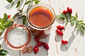 Homemade rose hip jelly in an open jar on a garden table