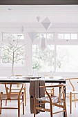 Modern dining table with classic chairs in white, stylized tree and paper tags as Christmas decorations