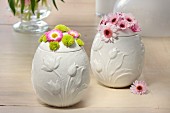 White, egg-shaped china pots decorated for Easter with spring flowers