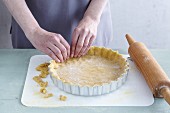 Gluten-free shortcrust pastry being pushed into a baking dish