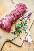 Ready-to-cook beef roulade with ingredients on a wooden chopping board