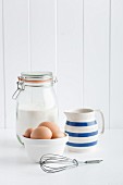 Eggs, flour, a jug of milk and whisk