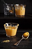 Two glass jars of lemon curd on a dark wooden table