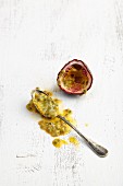 A halved passion fruit and a spoon with scooped-out fruit flesh