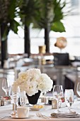 A table laid in white at a wedding reception with a bunch of white flowers