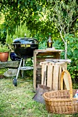 A wooden charcoal grill, wooden boxes and a basket in a garden