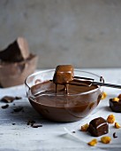 A praline being lifted out of a bowl of melted chocolate