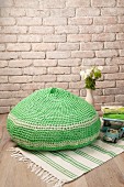 Crocheted green pouffe on green and white rug