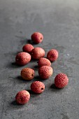 Lychees scattered on a grey stone surface