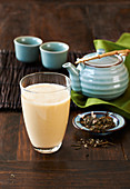 Grüntee-Frucht-Smoothie mit asiatischer Teekanne und Teebechern im Hintergrund