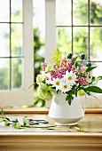 A bunch of fresh cut summer flowers in a white vase