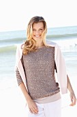 A young woman on a beach with a jumper over her shoulders