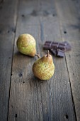 Two pears and pieces of chocolate on a wooden surface