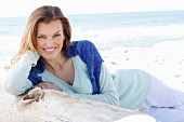 A young woman on a beach with a jumper over her shoulders