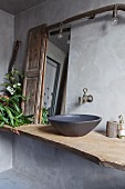 Black vessel sink on vintage wooden board and light bulbs in vintage bathroom