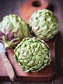 Fresh artichokes on a rustic wooden chopping board