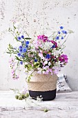 A summer bouquet of cornflowers, vetches, wild carrots and globa amaranth in a vase