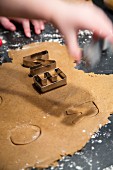 Hands cutting letters out of biscuit dough