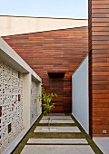 Courtyard of contemporary, Indian house with wood-clad façade and traditional Jali (perforated stone screen)