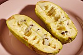 Ripe pawpaws, halved, on a pink plate