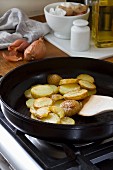 Sliced potatoes being fried in a pan