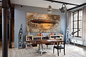 Tabletop on extravagant metal base and modern artwork on grey wall in loft apartment