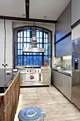 Stainless steel kitchen and industrial window in loft apartment