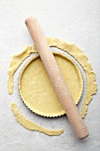 A tart being made: excess pastry being removed from the edge with a rolling pin