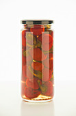 Pickled peppers in a screw-top jar on a white surface