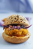A vegan burger made from chickpeas, millet and sweet potatoes on a wholemeal roll with red cabbage salad and mango sauce