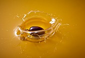 A black olive falling into olive oil