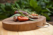 A wooden platter with various sausages and herbs