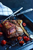 Roast pork roulade with braised cocktail tomatoes on a baking tray